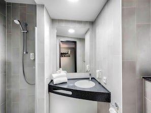A modern bathroom with a shower, a sink, and a mirror. - Ibis Budget Flensburg City (Flensburg)