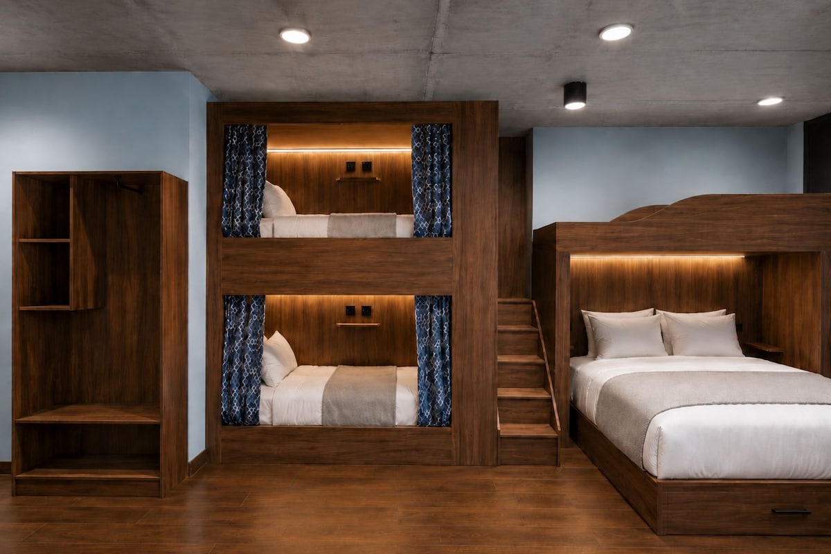 Une chambre avec des lits superposés à plusieurs niveaux, dotée d’étagères intégrées et d’un escalier.