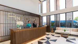 Un mostrador de recepción de diseño moderno, dos empleados y un suelo con estampado geométrico.