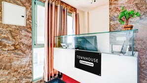 A reception desk with a sign indicating it's a company-serviced area, a glass railing, and a stone wall. - Townhouse Mysuru Sand Museum (Mysore)