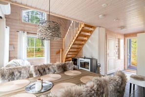A wooden interior with a dining area, a staircase, and a view of the outdoors. - Kaakkoishovi by Aavalevi (Levi)