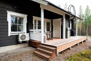 A cabin with a porch, a table, and a chair. - Kaakkoishovi by Aavalevi (Levi)