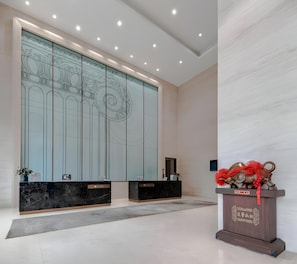 En reception med marmorerede borde, en dekorativ væg med traditionelt design og et træskab med rød detalje.