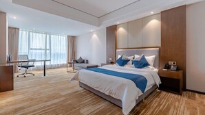 Ein modernes Hotelzimmer mit einem großen Bett, einem Schreibtisch und einem Stuhl.