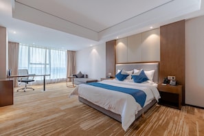Et moderne hotelværelse med en stor seng, et skrivebord og en stol.