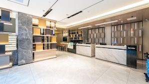 A modern hotel lobby with marble reception desks, a seating area, and a view of the sky. - Echarm Hotel (Guilin)