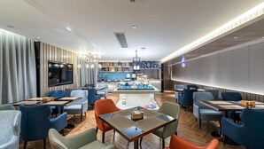 A modern hotel lobby with a bar area, seating arrangements, and a television screen. - Echarm Hotel (Guilin)