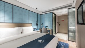 A modern hotel room with a large bed, a desk, and a seating area. - Echarm Hotel (Guilin)