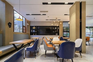 Een modern cafƩ interieur met houten tafels en stoelen, hanglampen en uitzicht door het raam.