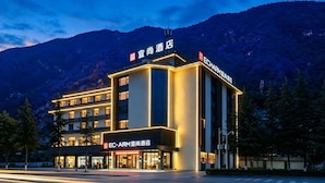 Um hotel com design moderno, com vários andares e uma placa chamativa.