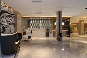 Een modern ingerichte receptie met een balie, zitplaatsen en een decoratieve wand.