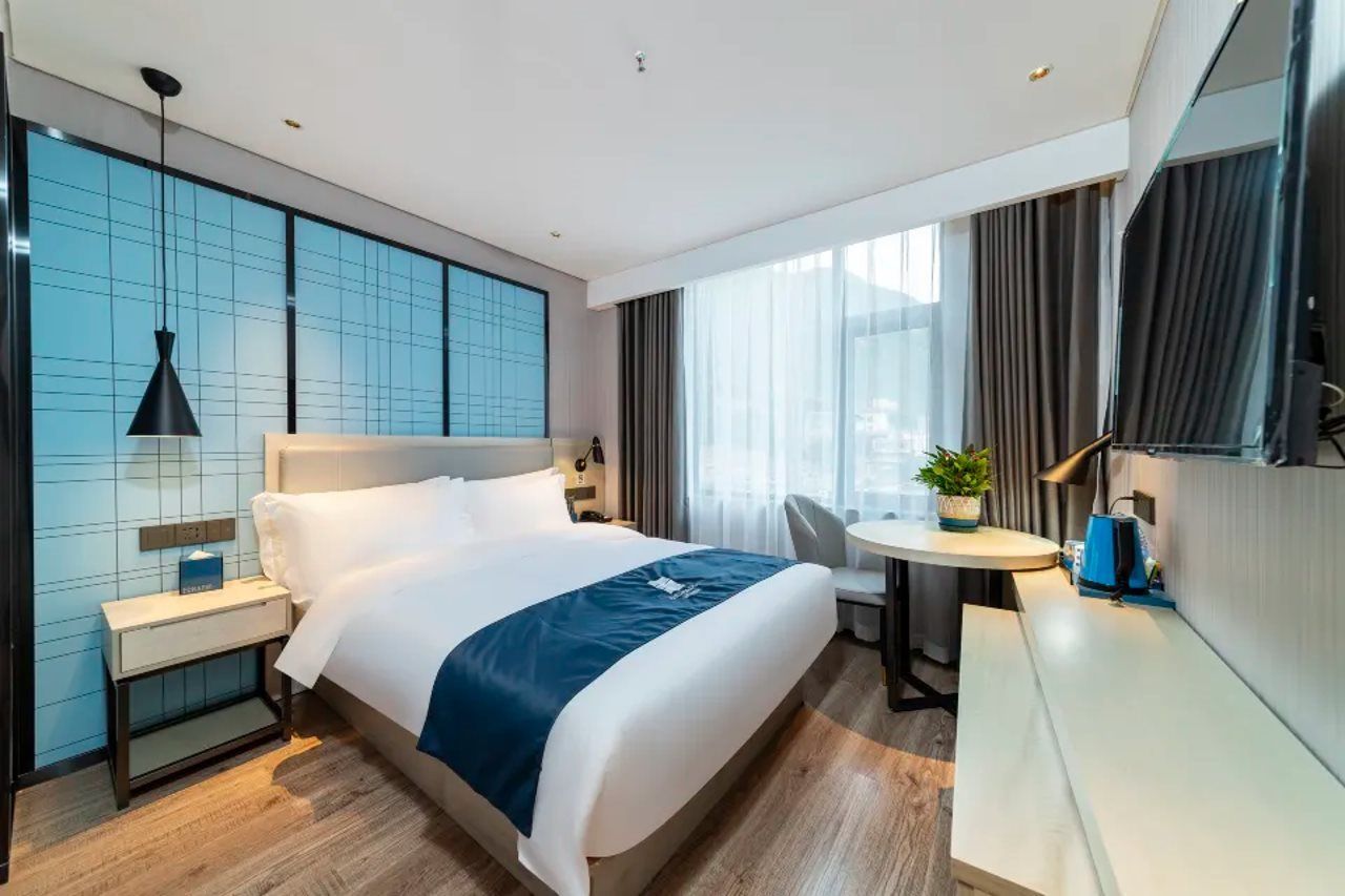 A modern hotel room with a large bed, bedside tables, a desk, and a chair.