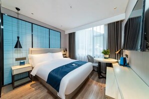 Een moderne hotelkamer met een groot bed, nachtkastjes, een bureau en een stoel.