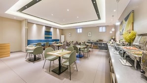 Uma área de refeições moderna com várias mesas e cadeiras, um balcão de buffet e um balcão de recepção de madeira.
