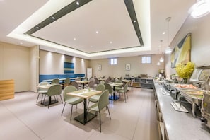 A modern dining area with multiple tables and chairs, a buffet counter, and a wooden reception desk. - Homeinn Selected (Weifang)