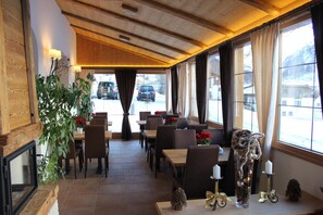 A restaurant with wooden interior, large windows, and a view of parked cars outside. - Waldpark Hotel Garni (Samnaun)