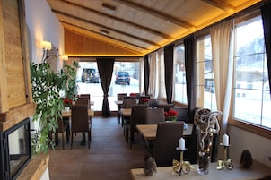 Un restaurante con interior de madera, amplias ventanas y vista a coches estacionados afuera.