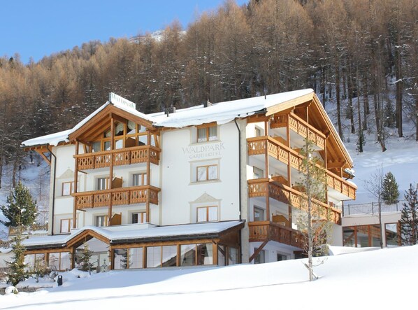 A multi-story hotel with wooden balconies and a snow-covered roof. - Waldpark Hotel Garni (Samnaun)