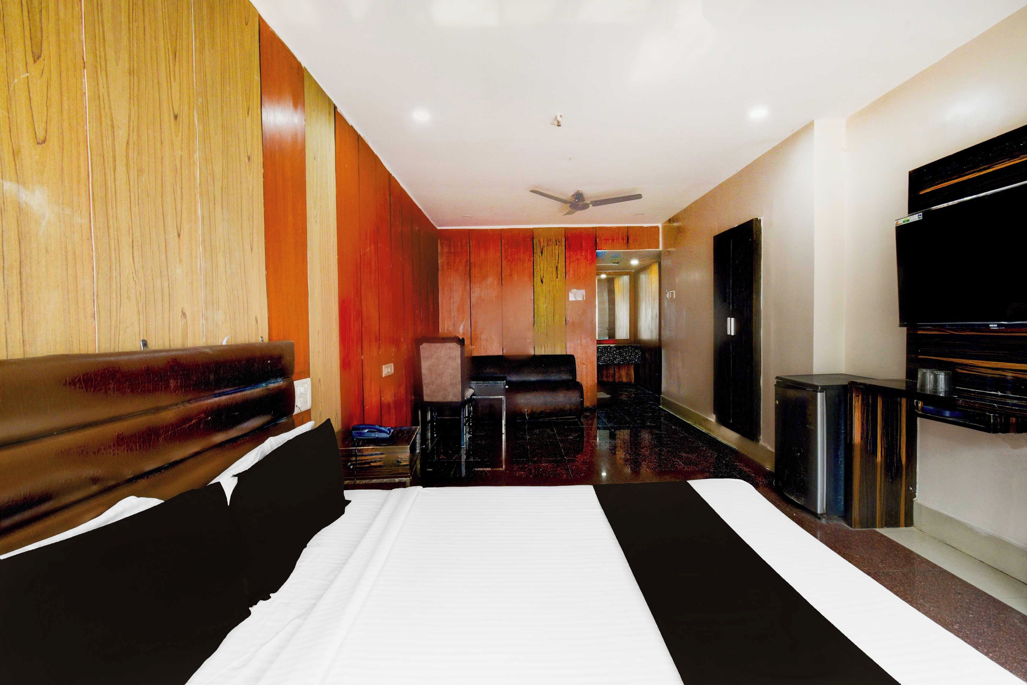 Une chambre d’hôtel avec un grand lit, un canapé, une télévision et un ventilateur de plafond.