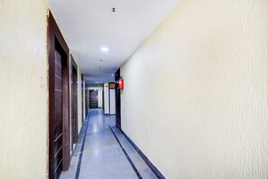 A long, narrow hallway with doors on one side and a fire extinguisher mounted on the wall. - Townhouse Oak Narayanaguda Metro Station (Hyderabad)