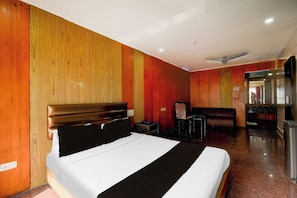 Una habitación de hotel con una cama, un escritorio, una silla y un espejo.