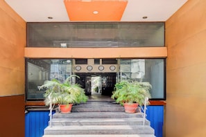 A hotel entrance with a double staircase, potted plants, and a glass wall. - Townhouse Oak Narayanaguda Metro Station (Hyderabad)