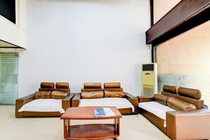 A hotel room with a sofa set, a wooden coffee table, and a standing air conditioner. - Townhouse Oak Narayanaguda Metro Station (Hyderabad)