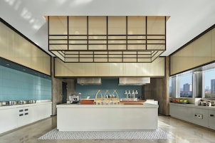 Una cocina moderna con una isla central, un salpicadero azul y vistas a la ciudad a través de grandes ventanales.