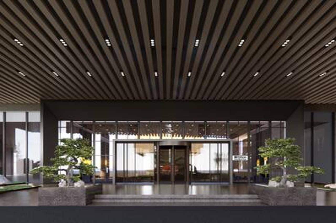 Una entrada moderna a un edificio con techo inclinado y puertas de vidrio.