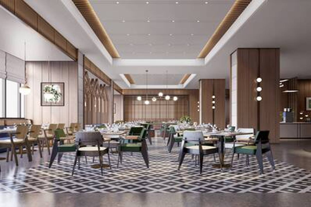 A modern hotel dining area with multiple tables and chairs, a patterned floor, and pendant lighting.