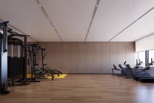 Un gimnasio moderno con equipamiento de ejercicio, suelo de madera y un ventanal grande.
