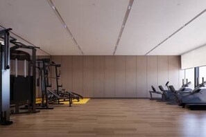 A modern gym with exercise equipment, wooden flooring, and a large window.
