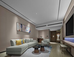 A modern living room with a sectional sofa, two round coffee tables, a flat-screen TV, and abstract wall art.