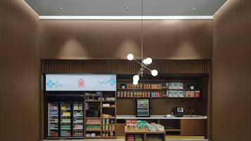 Un espacio comercial moderno con una máquina expendedora, estantes llenos de aperitivos y una caja registradora.