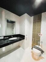 A modern bathroom with a black countertop sink, a glass-enclosed shower, and a toilet with a towel hanging on the wall.