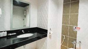 Un baño con lavamanos de encimera negro, espejo, inodoro y zona de ducha.