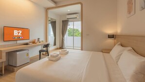 A hotel room with a bed, a desk, a chair, a television, and a view of the outdoors. - B2 Map Ta Phut Boutique & Budget Hotel (Rayong)
