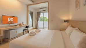 Une chambre d’hôtel équipée d’un lit, d’un bureau, d’une chaise, d’une télévision et offrant une vue sur l’extérieur.