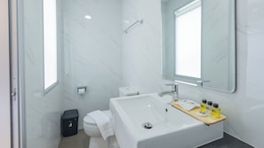 Une salle de bain moderne avec un lavabo, un miroir et des toilettes, le tout de couleur blanche.
