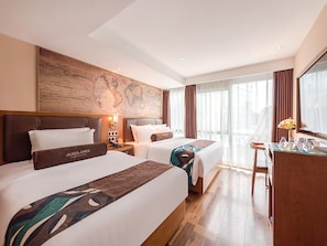 Habitación de hotel con dos camas, un escritorio, un mapa en la pared y vistas de la ciudad.