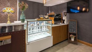 A modern coffee shop interior with a glass display case, coffee machines, and a chalkboard menu. - James Joyce Beijing Chongwenmen Tiantan Qiaowan Subway Station (Beijing)