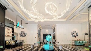 Un hall d’hôtel avec un sol à carreaux, un espace salon central et un design de plafond moderne.