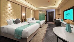 Une chambre d’hôtel avec deux lits, un bureau, une télévision et une salle de bain visible à travers une porte en verre.