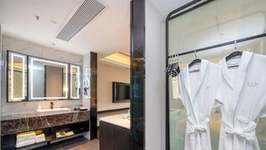 Une salle de bain moderne dotée d’un grand miroir, d’un meuble-lavabo et d’une cabine de douche en verre.