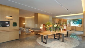 En moderne hotellobby med reception, siddeområde og et stort vindue med udsigt.