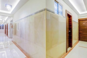 A hotel corridor with a modern design, featuring a marble floor, a wooden door, and a ceiling with a skylight.