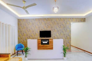 A reception area with a modern design, including a reception desk, a ceiling fan, a chandelier, and a patterned wall.