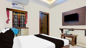 Une chambre d’hôtel équipée d’un lit, d’un bureau, d’une chaise, d’un téléviseur fixé au mur et d’un appareil de climatisation.