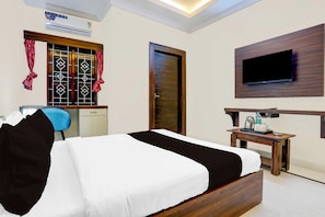 Une chambre d’hôtel équipée d’un lit, d’un bureau, d’une chaise, d’un téléviseur fixé au mur et d’un appareil de climatisation.