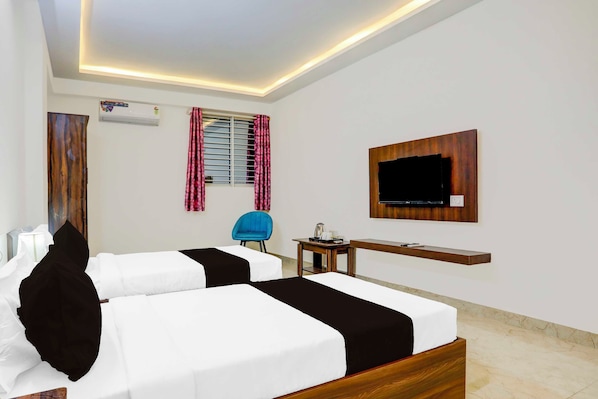 A hotel room with two beds, a TV mounted on the wall, a small table, and a chair.